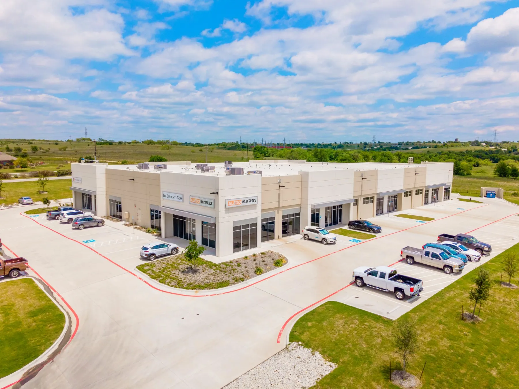 Aerial view of Champions Business Park in Aledo — Westbrook's tan-and-white industrial-flex building, home to Aledo Workspace, under a wide Texas sky.