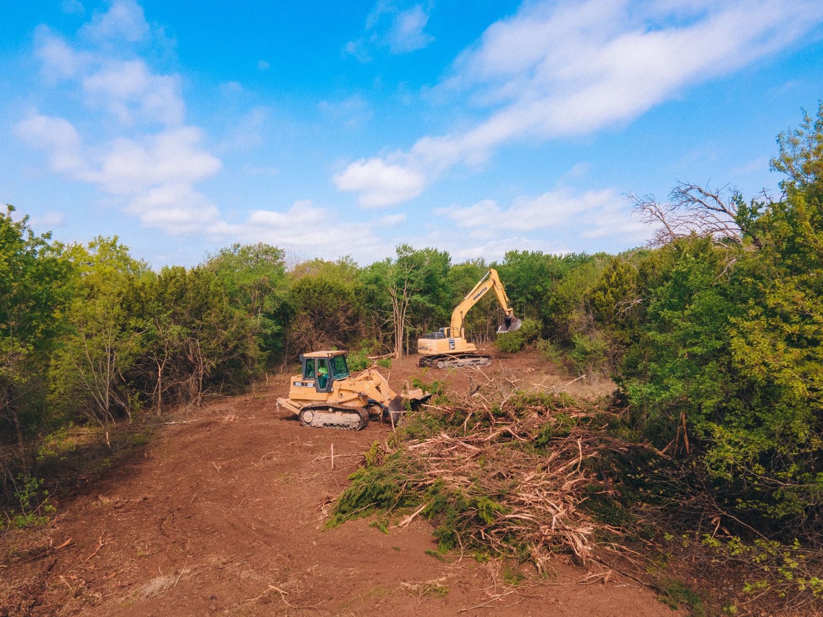 A dozer and excavator clearing ground at an Aledo River site — work underway in concert.